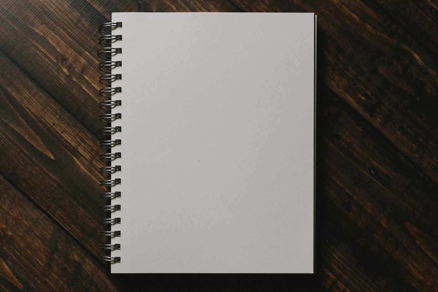 Cuaderno encuadernado en espiral sobre una mesa de madera oscura